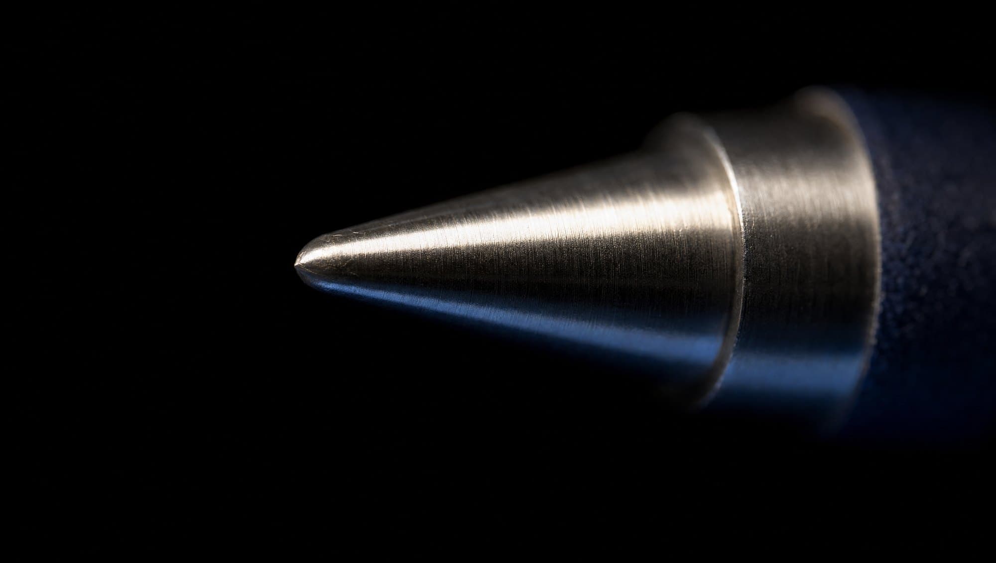 Macro detail of the polished silver tip of the crayon against its navy body